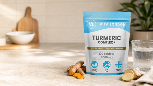 Vita London Turmeric Complex+ pouch, 120 tablets, on a sunlit kitchen counter with fresh turmeric root, ginger and a glass of water